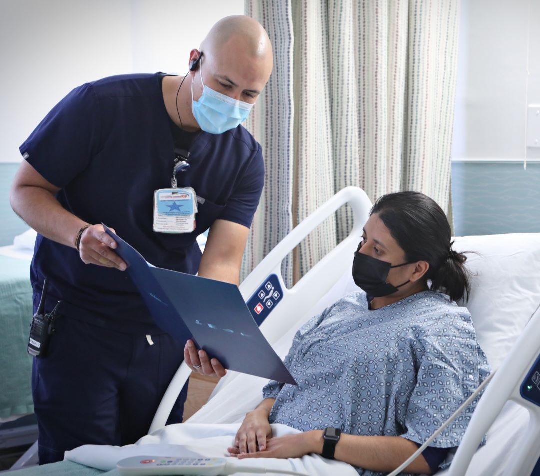 Medical staff showing tablet to elderly patient